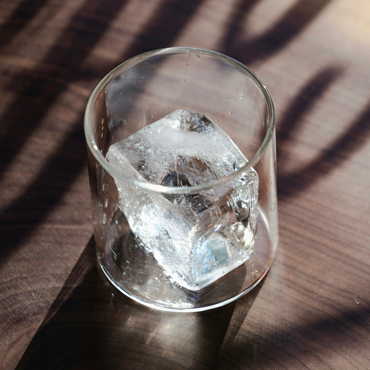 A glass of ice sitting on top of a wooden table