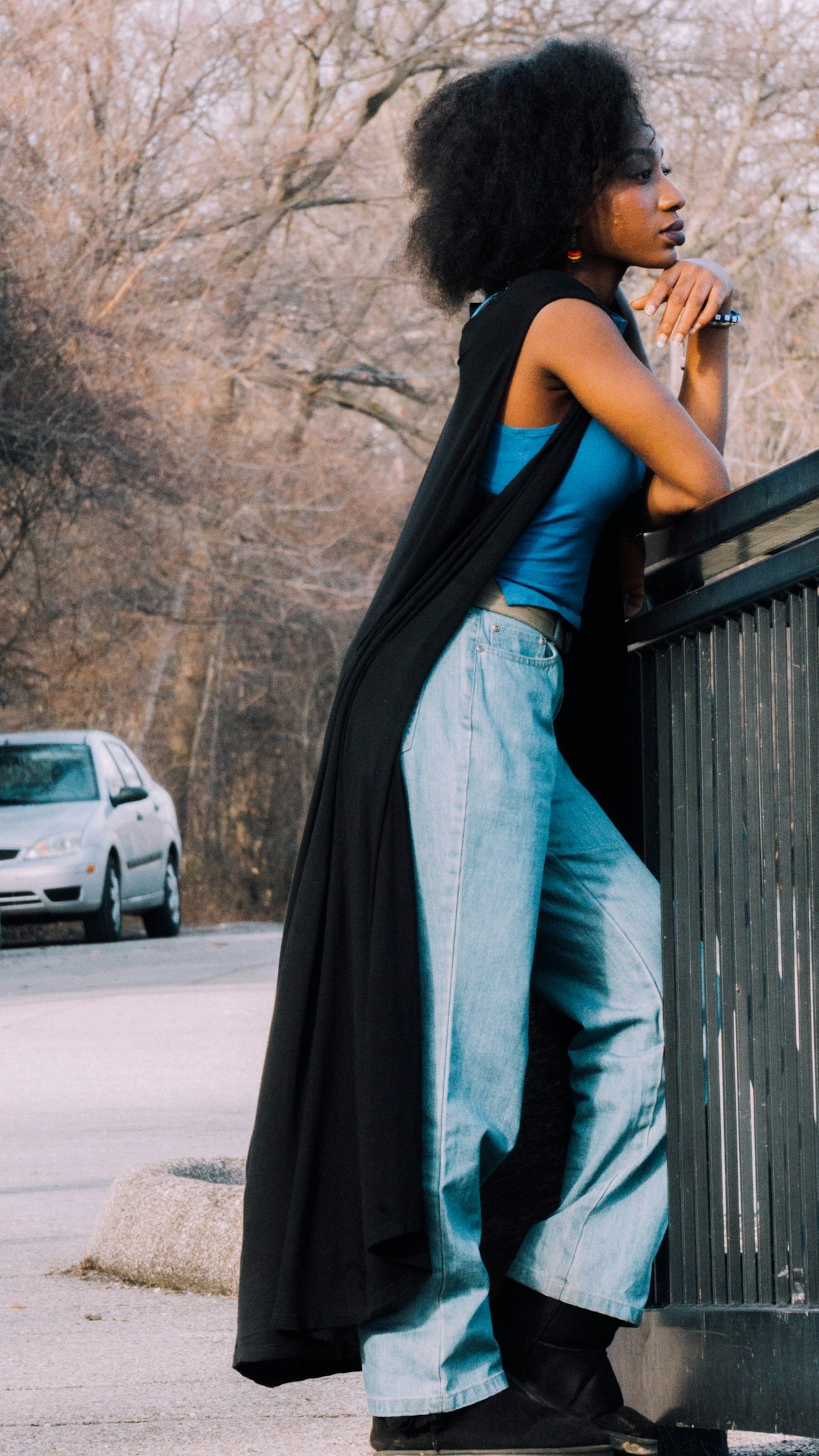 woman in black shirt and blue denim jeans leaning on wooden fence