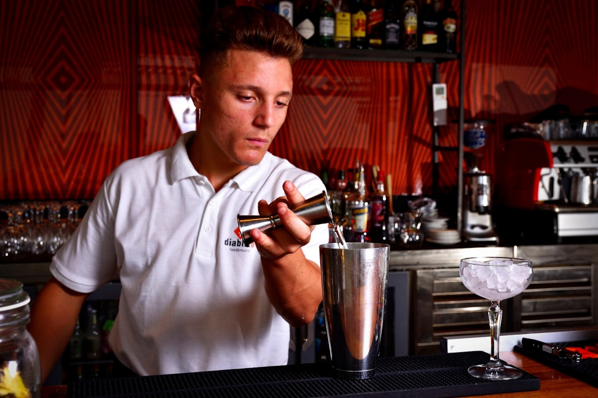 a man is making a drink at a bar