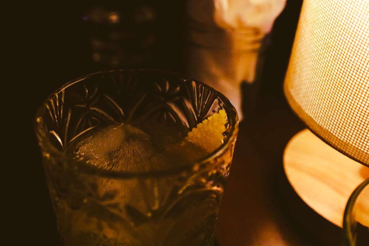 a close up of a glass next to a lamp