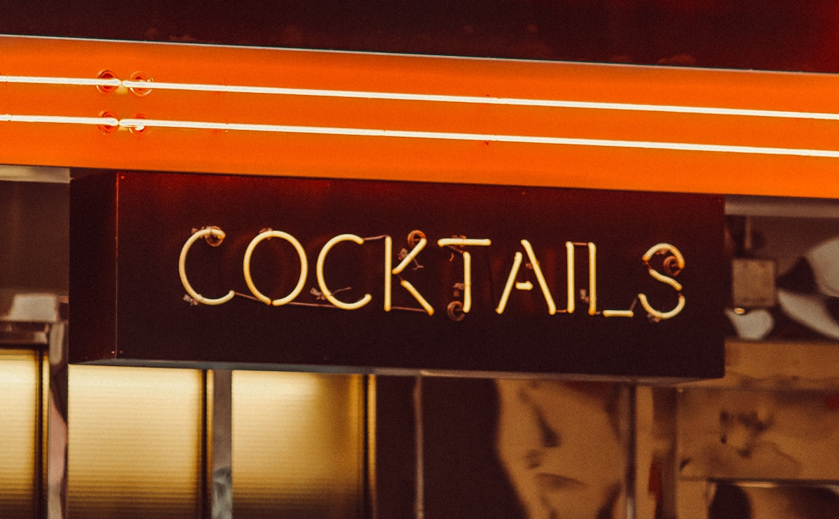 a sign that says cocktails hanging from the side of a building