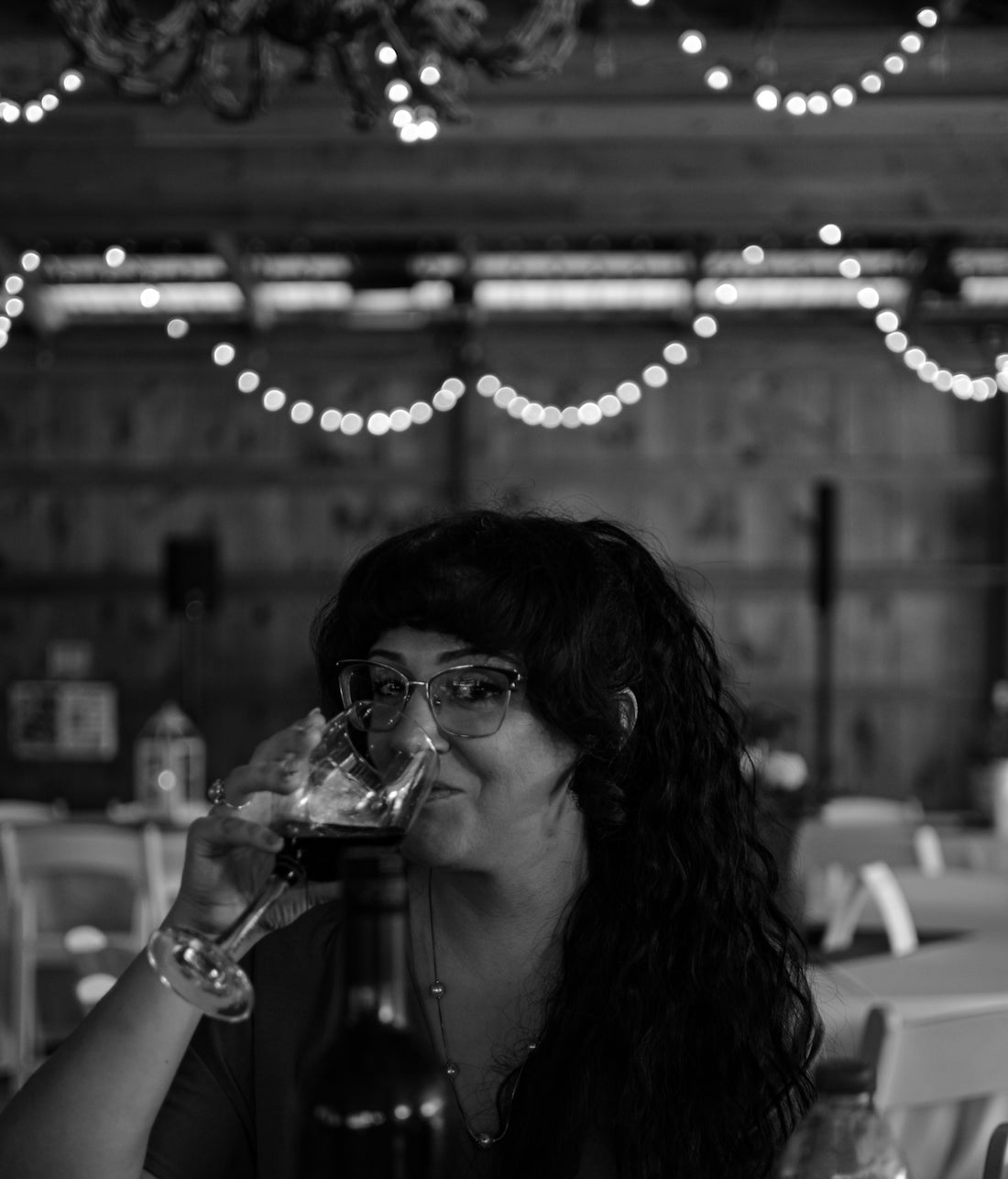 a woman sitting at a table drinking a glass of wine