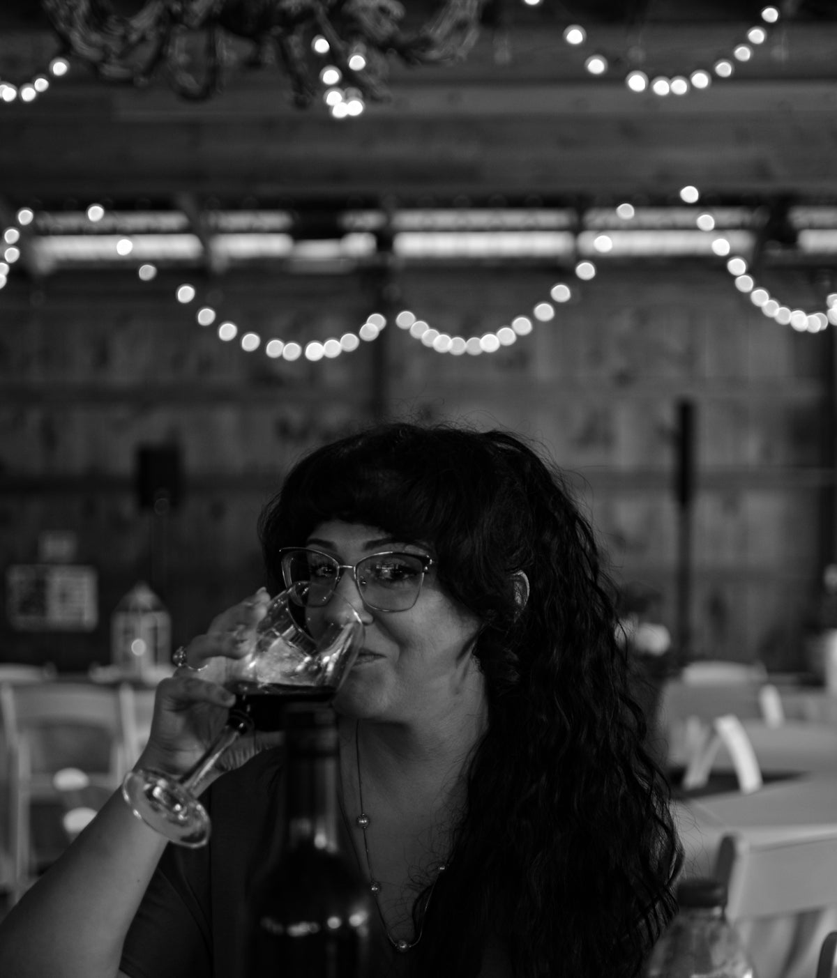 a woman sitting at a table drinking a glass of wine