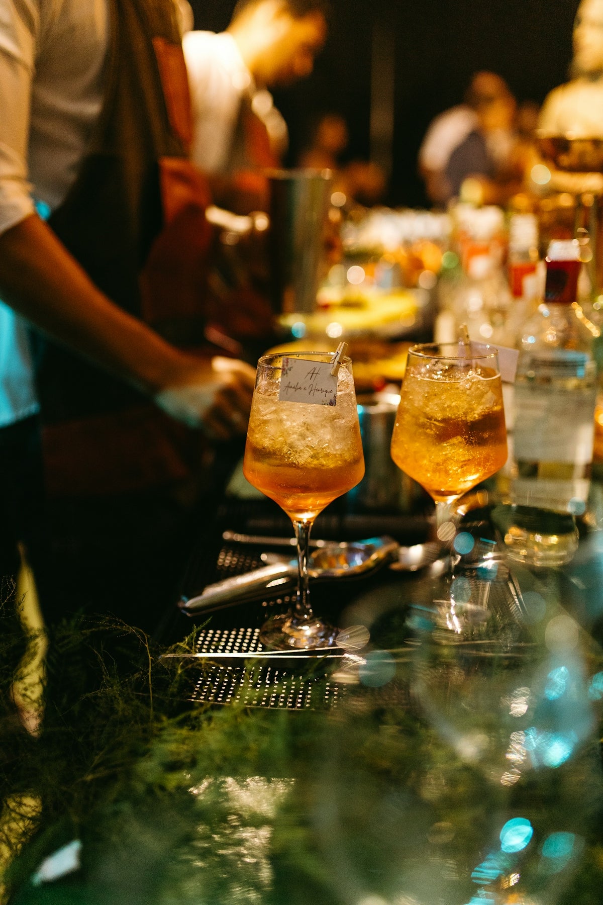 Several glasses of alcohol are lined up on a bar