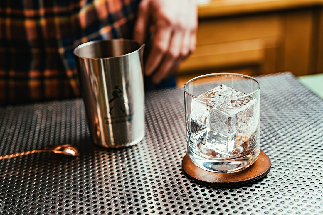 A cocktail with ice cubes on a coaster